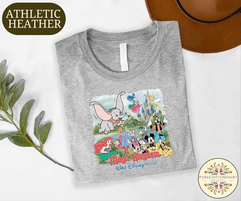 A gray t-shirt with a Disney-themed graphic design, including characters from the Disney animated films, is displayed on a white surface.