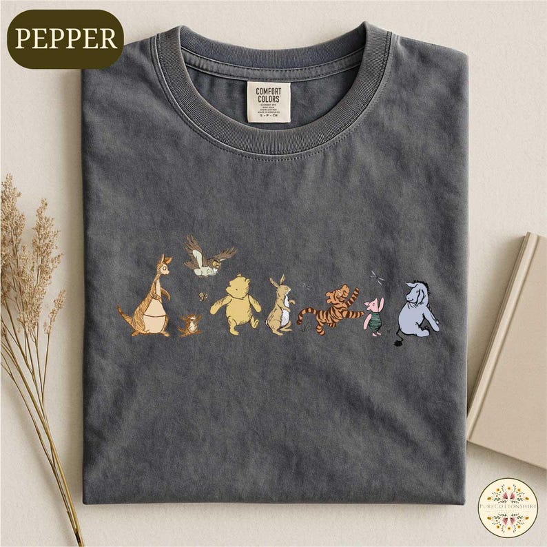 A gray t-shirt with a printed design of various cartoon animal characters, including a kangaroo, bear, tiger, and elephant, arranged in a row.