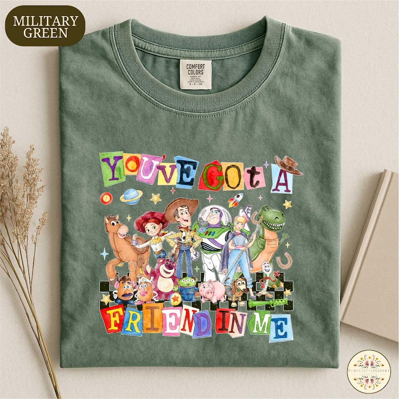A green t-shirt with a colorful graphic design featuring characters from the Toy Story franchise, including Woody, Buzz Lightyear, and other beloved characters.