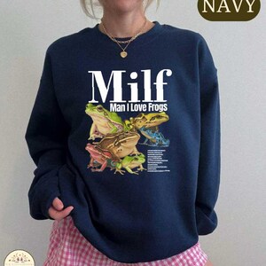 A navy blue sweatshirt with a graphic design of various colorful frogs.