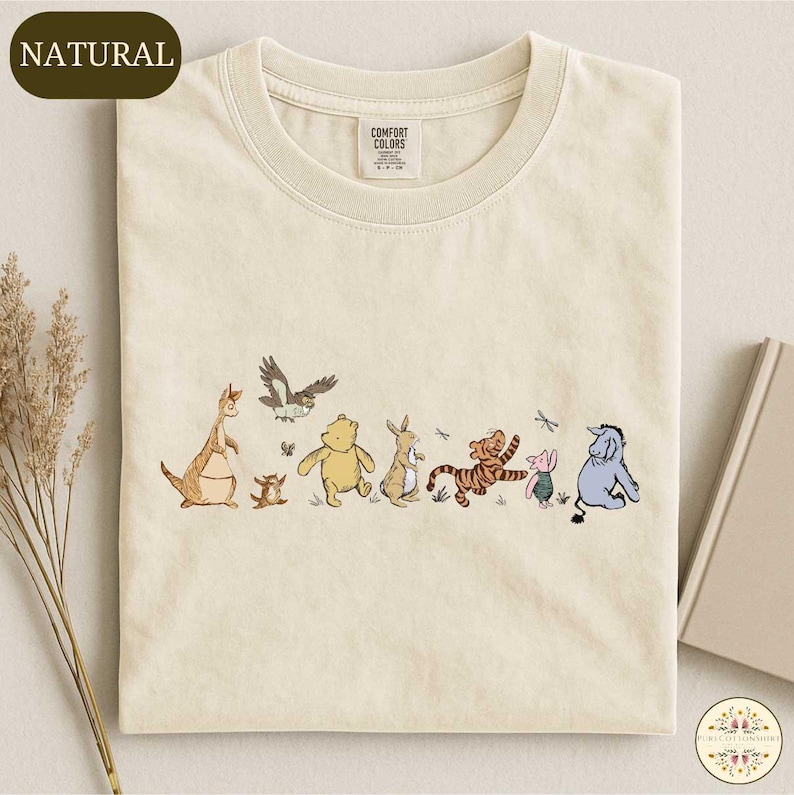 A t-shirt with a printed design of various Winnie the Pooh characters, including Tigger, Tigger's friend, and other beloved characters.