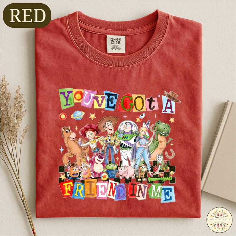 A red t-shirt with a colorful graphic design featuring characters from the Toy Story movie, along with the text "You've got a friend in me".