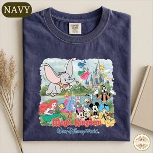 A navy blue t-shirt with a colorful graphic design depicting various Disney characters and the text "Magic Kingdom Walt Disney World."