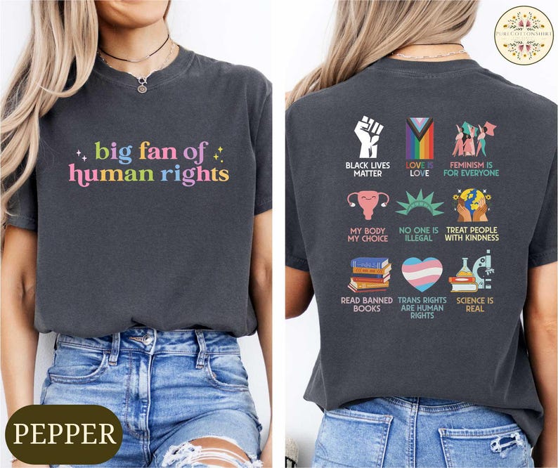 May include: Dark gray t-shirt with the text "big fan of human rights" in colorful letters. The back of the shirt features various social justice symbols and phrases, including "Black Lives Matter" and "Love is Love".