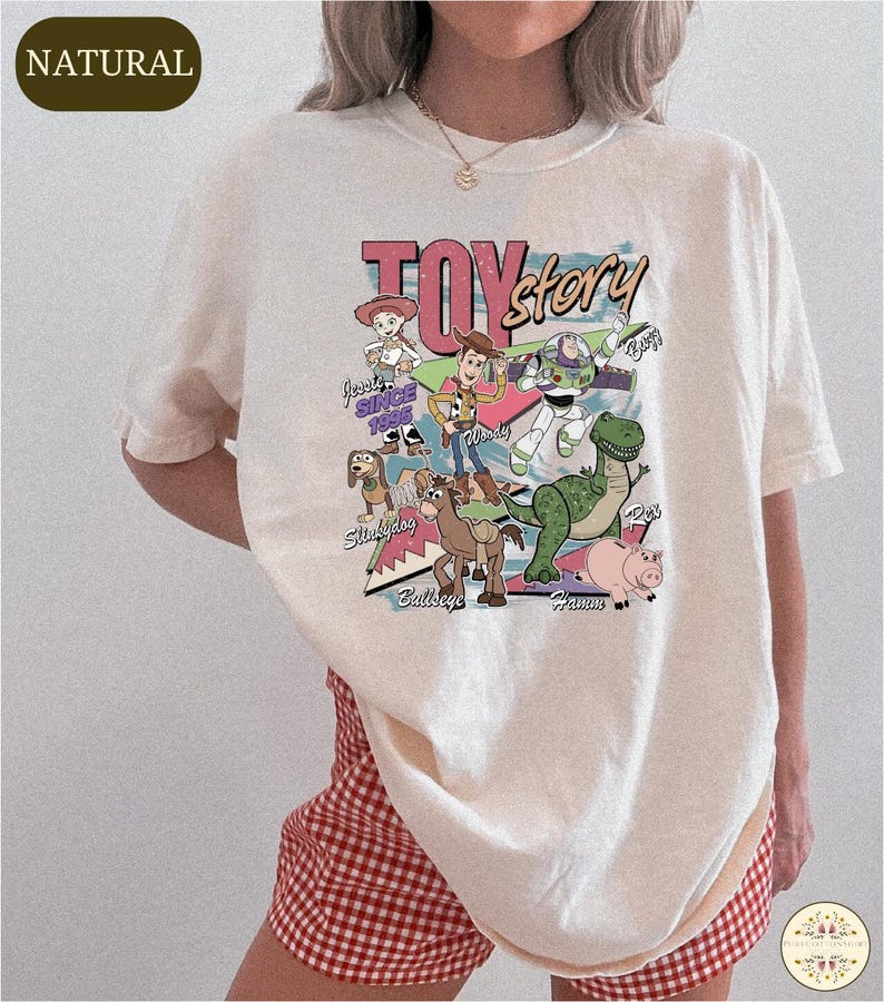 A person wearing a white t-shirt with a colorful graphic of characters from the Toy Story movie.