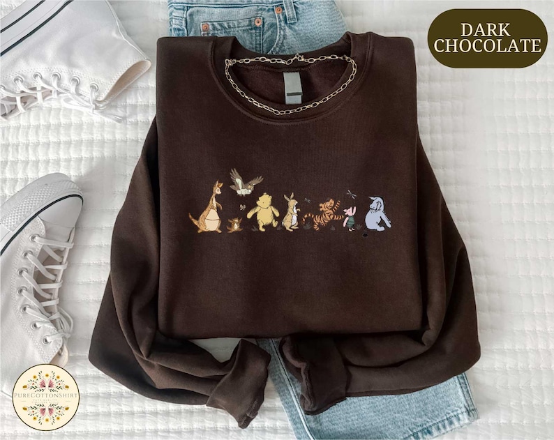 a brown sweatshirt with a line of cartoon animal characters printed on it, along with a pair of jeans and sneakers.