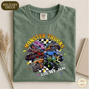 A military green t-shirt with a graphic design of various monster trucks and the text "MONSTER TRUCKS ARE MY JAM" printed on it.