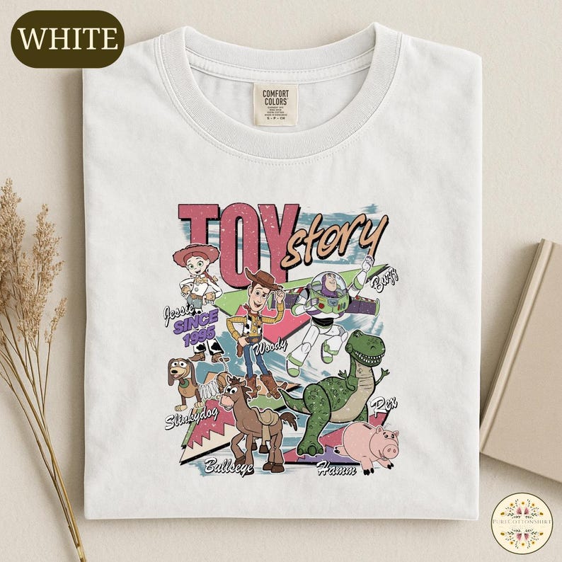 A white t-shirt with a colorful graphic design featuring characters from the Toy Story movie, including Woody, Buzz Lightyear, and other beloved characters.