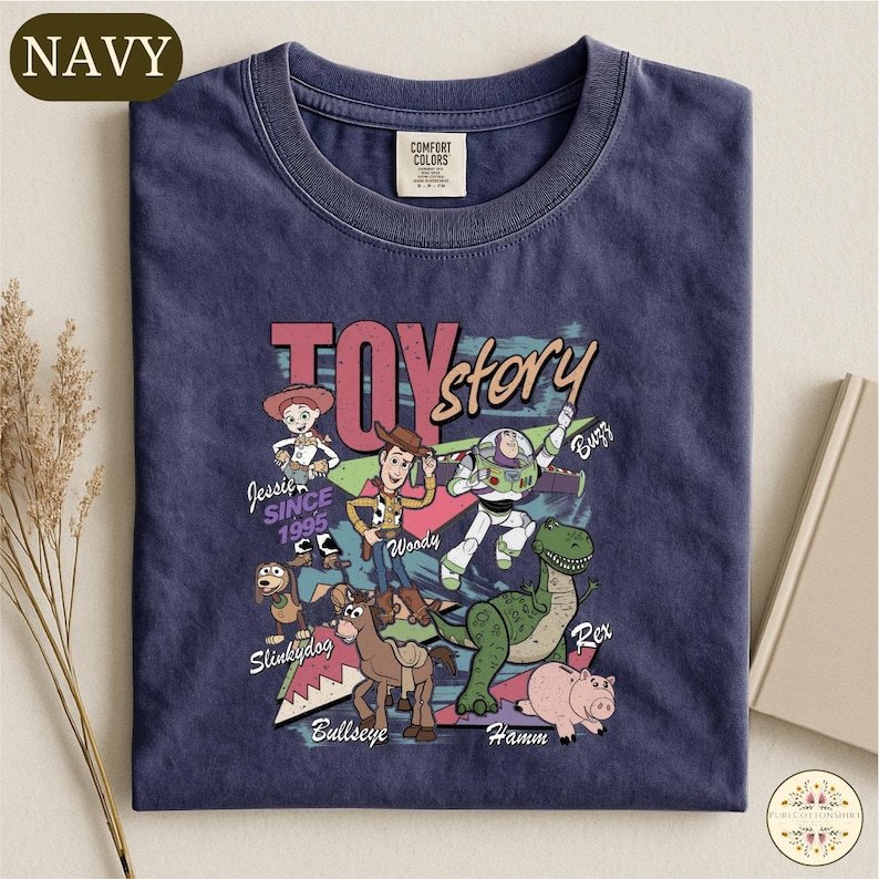 A navy blue t-shirt with a colorful graphic design featuring characters from the Toy Story movie, including Woody, Buzz Lightyear, and other beloved characters.