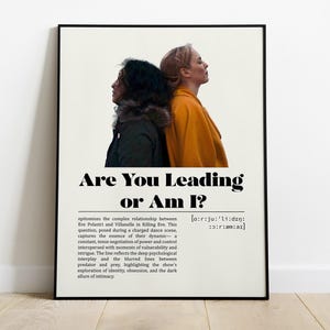 Może przedstawiać: Oprawiony plakat z napisem "Are You Leading or Am I?" i dwoma kobietami w profilu. Jedna ma na sobie czarną kurtkę, druga pomarańczowy płaszcz. Plakat jest na białym tle.