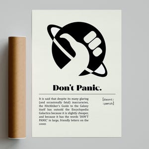 Könnte beinhalten: Ein Poster mit den Worten "Don't Panic" in fetten, schwarzen Buchstaben. Das Poster zeigt eine schwarz-weiße Grafik einer Hand in einem Ringplaneten. Links vom Poster befindet sich eine braune zylindrische Röhre.