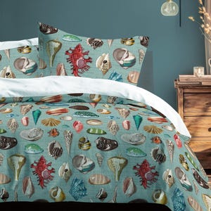 May include: A bed set with a teal duvet cover and pillowcases decorated with a seashell pattern in various colours. The bedding includes a white fitted sheet. The room has a wooden bedside table and a wall-mounted lamp.
