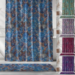 May include: A blue and brown patterned shower curtain and matching bath mat. The design features a damask pattern in shades of blue, brown, and gray. The bathroom decor also includes a white bathtub, a woven basket, and decorative plants.