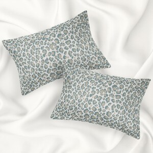 May include: Two decorative throw pillows with a light blue and beige leopard print pattern.