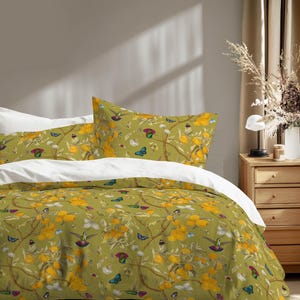 May include: A bed with a green floral patterned duvet cover and pillowcases. The pattern includes yellow flowers, butterflies, and hummingbirds. The bed has white sheets and is set against a neutral-colored wall.