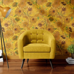 May include: A yellow armchair with button tufting sits in front of a wall covered in sunflower wallpaper. A black tripod floor lamp with a yellow shade is to the left of the chair. There are books stacked on the floor next to the lamp.