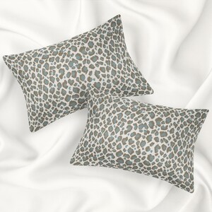 May include: Two decorative throw pillows with a brown and blue leopard print pattern. The pillows are on a white background.