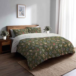 May include: A bed with a green paisley patterned duvet cover and matching pillowcases. The bedding features a white underside and is set on a wooden bed frame. The room has a neutral color palette with a framed artwork and a woven rug.