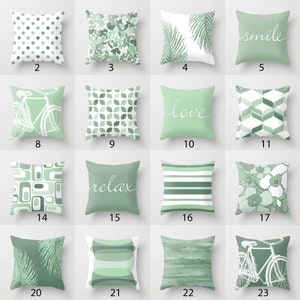 May include: Twenty-four different green throw pillow designs with various patterns, including geometric shapes, floral designs, bicycles, and text. The text on the pillows includes "smile", "love", "relax", and "Shroom Queens".