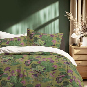 May include: A bed with a green and purple floral patterned duvet cover and pillowcases. The bedding features a botanical design with large leaves and flowers. The bed is made up with a white top sheet. The room has a green wall and a wooden nightstand.