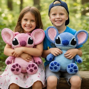 May include: Two children holding large, handmade crochet plush toys. One is pink with large ears and black eyes, the other is blue with similar features. The toys have detailed stitching and are designed to resemble cartoon characters.