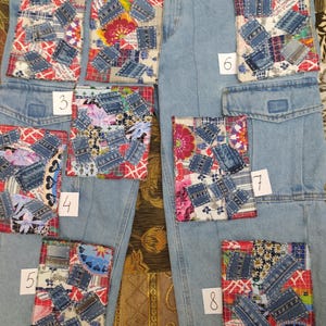 Könnte beinhalten: Hellblaue Jeanshose mit acht farbenfrohen Patchwork-Designs. Jeder Patch enthält eine Mischung aus Jeansstoffstücken und gemusterten Stoffen in verschiedenen Farben, darunter Rot, Blau und Blumendrucke. Die Patches sind mit 1 bis 8 nummeriert.