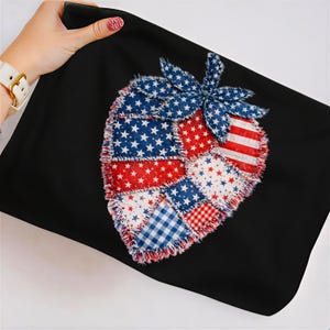 May include: Black pillowcase featuring a patriotic strawberry design. The strawberry is made of patchwork fabric with red, white, and blue patterns, including stars and stripes. A blue flower with star patterns sits at the top.