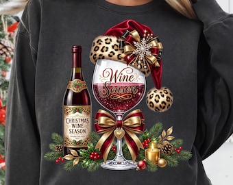 Può includere: Una felpa grigio antracite con la grafica di una bottiglia di vino e un calice. Il calice indossa un cappello da Babbo Natale leopardato con un fiocco dorato. L'etichetta riporta Christmas Wine Season e il calice il testo Wine Season.