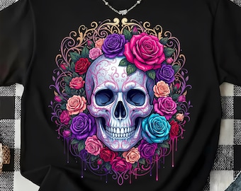 Può includere: Una t-shirt nera con una grafica centrale raffigurante un teschio bianco decorato con intricati motivi in filigrana rosa. Il teschio è circondato da una vivace composizione di rose nei toni del rosso, rosa, viola e blu, su una cornice dorata.