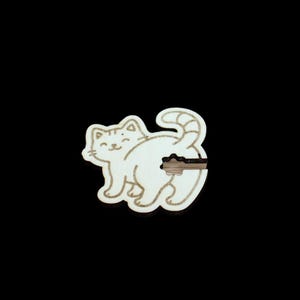 Può includere: Un tappo per bottiglia a forma di gatto in legno. Il gatto è bianco con un contorno marrone chiaro e strisce sulla coda. Il gatto ha una faccia sorridente e un tappo a forma di chiave inserito nella parte posteriore. Lo sfondo è nero.