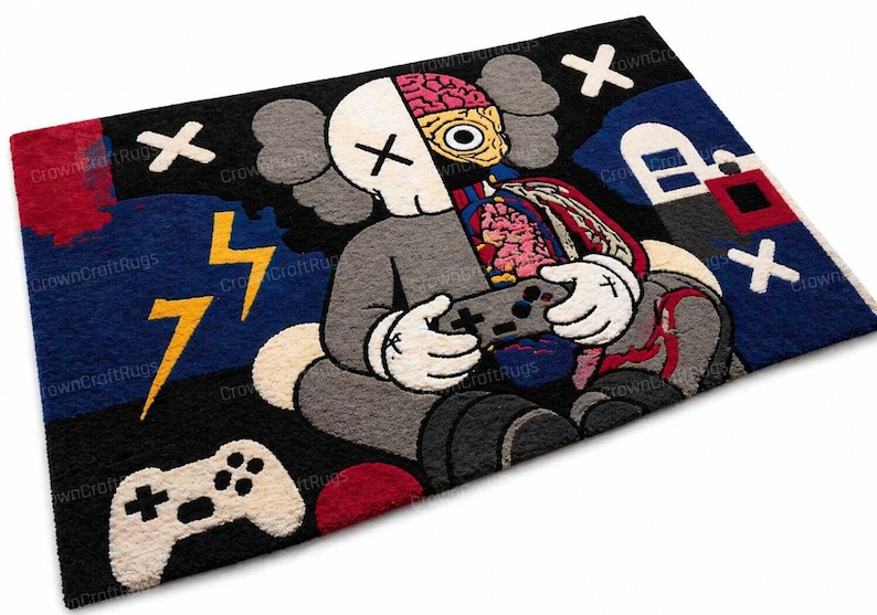 May include: A rectangular rug featuring a cartoon character with a split skull revealing the brain and internal organs, holding a game controller. The rug has a black background with blue, red, and yellow accents, including lightning bolts and a game controller.