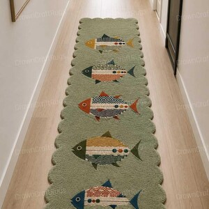Könnte beinhalten: Ein grüner Läufer mit gewelltem Rand, der ein sich wiederholendes Muster aus bunten Fischen zeigt. Jeder Fisch hat ein einzigartiges Design mit Gelb-, Blau-, Orange- und Rottönen. Der Teppich liegt in einem Flur mit Holzboden.