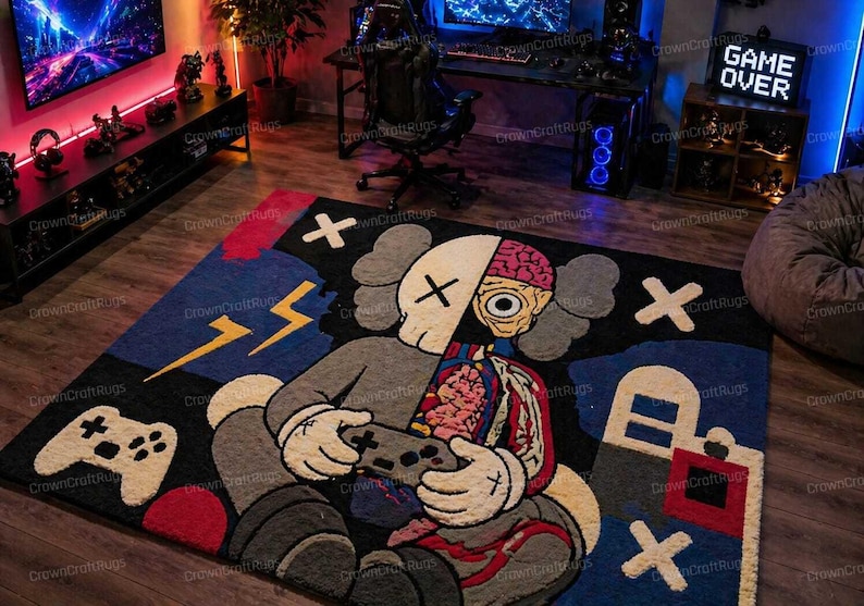 May include: A large, rectangular rug with a cartoon character design. The rug features a figure holding a game controller, with a split design showing internal anatomy. The color palette includes black, gray, blue, red, and yellow accents. The rug is designed for a gaming room.
