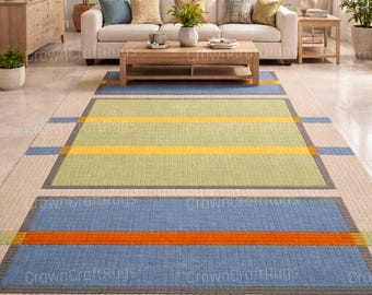 May include: A rectangular area rug with a geometric design. The rug features a beige border, with sections of blue, green, and orange stripes. The rug is placed in a living room setting with a white sofa and wooden furniture.