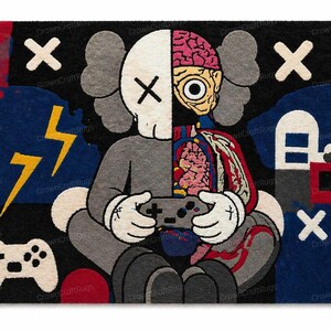May include: A rectangular rug featuring a cartoon character design. The character is split, with one side showing a skull and the other side revealing internal organs. The character is holding a video game controller. The rug has a black background with white X's and a yellow lightning bolt.