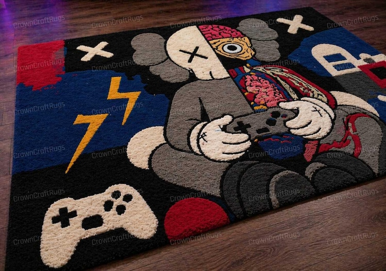 May include: A large, rectangular rug featuring a cartoon character holding a video game controller. The character is gray with white gloves and a partially exposed brain. The rug has a black, blue, and red color scheme with lightning bolt and controller graphics.