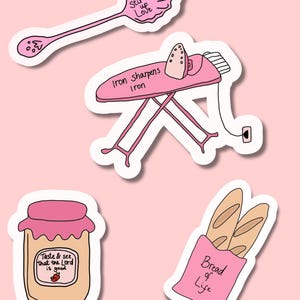 May include: A set of pink and white stickers with uplifting quotes. The stickers feature a spoon with "Stir up Love", an ironing board with "Iron Sharpens Iron", a jar with "Taste & see that the Lord is good", and a bag of bread with "Bread of Life".