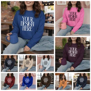 Peut inclure: Plusieurs sweat-shirts à col rond de différentes couleurs, chacun affichant le texte "YOUR DESIGN HERE" en blanc. Les sweat-shirts sont portés par des mannequins, mettant en valeur le design sur le devant. Chaque modèle tient une tasse.