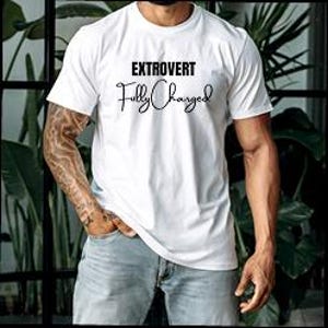 Puede incluir: Camiseta blanca con las palabras "EXTROVERT" sobre "Fully Charged" en una fuente de escritura. La camiseta tiene mangas cortas y cuello redondo. La persona lleva vaqueros azules y tiene un tatuaje en el brazo.
