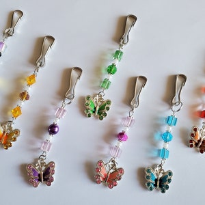 May include: Seven colourful butterfly charms with silver clips and crystal beads. Each charm features a different coloured butterfly with rhinestones.