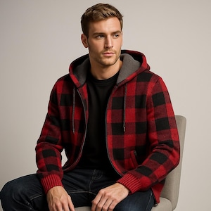 Op de afbeelding: Een rood-zwart geruit jack met capuchon en ritssluiting met een grijze voering. De jas heeft een geribde zoom en manchetten. De persoon draagt een zwart shirt en een blauwe jeans.