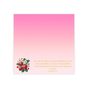 May include: A square notepad with a pink gradient background. A floral illustration of strawberries and leaves is in the lower left corner. Gold text reads "Do not be anxious about anything..." from Philippians 4:6.