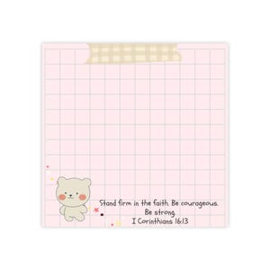 May include: A pink grid-lined sticky note with a cute bear illustration and text that reads "Stand firm in the faith. Be courageous. Be strong. I Corinthians 16:13". The note is held in place with tan tape.