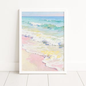 Könnte beinhalten: Ein gerahmter Kunstdruck einer Strandszene. Das Kunstwerk zeigt Meereswellen in Türkis- und Weißtönen, die an einen rosa-gelben Sandstrand gespült werden. Der Himmel ist ein sanftes Blau und Rosa. Der Druck ist in einem weißen Rahmen.