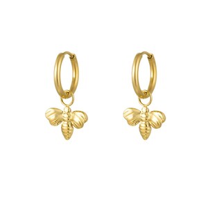 Könnte beinhalten: Ein Paar goldfarbene Creolen mit bienenförmigen Anhängern. Die Ohrringe bestehen aus glänzendem Metall und hängen an einem einfachen Reifen. Die Bienenanhänger haben detaillierte Flügel und Körpersegmente und verleihen einen Hauch von Natur.