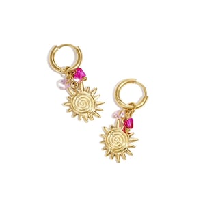 Könnte beinhalten: Ein Paar goldfarbene Creolen. Jeder Ohrring hat einen Sonnenaufgangs-Anhänger mit einem spiralförmigen Zentrum und baumelnden rosa und klaren Edelsteinen. Die Ohrringe sind zum Tragen am Ohr bestimmt.