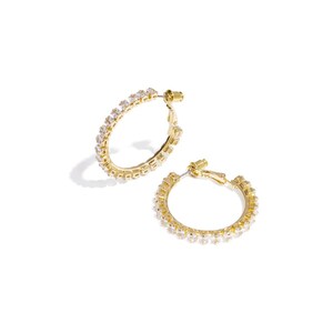 Könnte beinhalten: Zwei goldfarbene Creolen, jeweils besetzt mit kleinen, klaren Edelsteinen. Die Ohrringe werden vor einem weißen Hintergrund präsentiert, der ihre funkelnden Details hervorhebt. Die Creolen sind rund und haben ein klassisches Design.