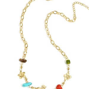 Könnte beinhalten: Goldfarbene Halskette mit Kettenglied-Design. Die Halskette hat Blumen- und Herzanhänger sowie türkisfarbene, rote und grüne Perlen. Eine braune Steinperle ist ebenfalls enthalten.