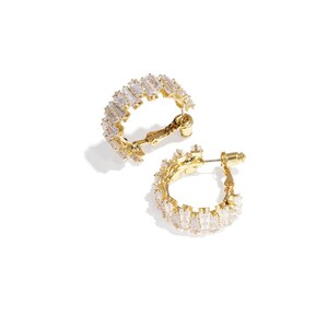 Könnte beinhalten: Ein Paar goldfarbene Creolen. Jeder Ohrring ist mit klaren, rechteckig geschliffenen Steinen besetzt. Die Ohrringe werden auf weißem Hintergrund gezeigt, wobei ein Ohrring geöffnet und der andere geschlossen ist.