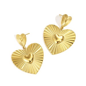 Könnte beinhalten: Ein Paar goldfarbene herzförmige Ohrringe. Jeder Ohrring hat einen großen Herzanhänger mit einem strukturierten Sonnenstrahl-Design und ein kleineres Herz oben. Die Ohrringe sind für durchbohrte Ohren konzipiert.